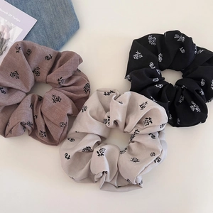 Detailed view of three large floral scrunchies in coffee, gray and black colors