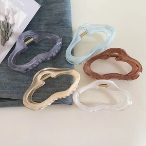 Close-up of five large wavy cloud hair claws in jelly colors on denim background