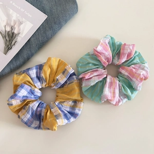 Detail of plaid scrunchies with frayed edges in blue-yellow and green-pink colorways
