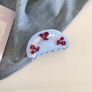 Detailed close-up of light blue cherry hair claw clip with sweet red fruit accents