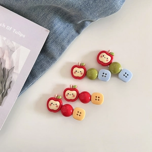 Vue détaillée de deux pinces à cheveux pomme avec perles colorées sur fond de tulipe