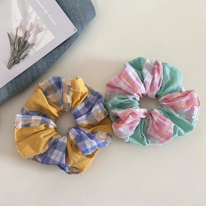 Detailed close-up of plaid fabric scrunchies with yellow and pink pastel checkered patterns