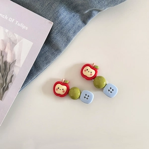 Détail de barrettes mignonnes en forme de pomme rouge et bouton bleu sur denim