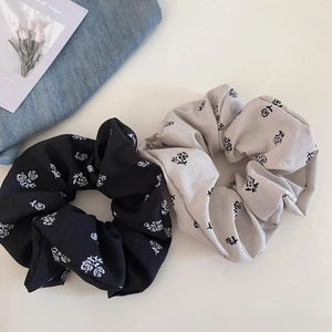 Macro detail of two rose print fabric scrunchies in black and grey on minimalist background