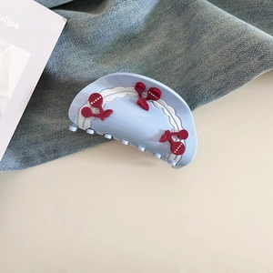 Detail showing the red cherry design and white wavy edge on a light blue hair claw clip