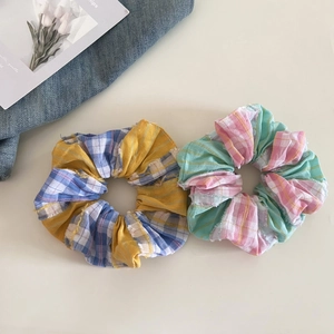 Detailed view of two checkered plaid scrunchies with vibrant colors and frayed edges
