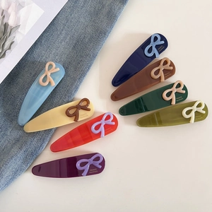 Détail de 8 barrettes à nœuds colorés avec gravure dorée France Handmade sur fond de tissu
