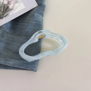 Detail of light blue cloud hair claw clip with golden spring on denim fabric
