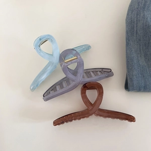 Détail de trois grandes pinces à cheveux aux couleurs gelée bleue, violette et marron sur denim