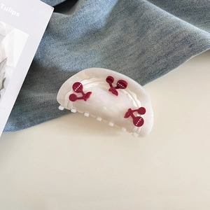 Macro detail of a cream-colored acetate cherry hair claw clip on a stylish background