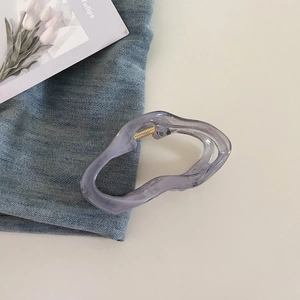 Detail of a translucent lavender cloud-shaped hair claw clip with golden spring mechanism