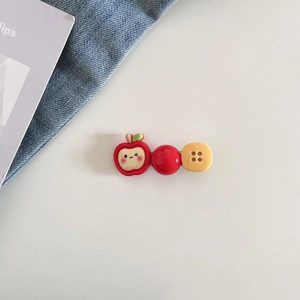 Gros plan de barrettes mignonnes avec pomme rouge et bouton jaune sur blanc