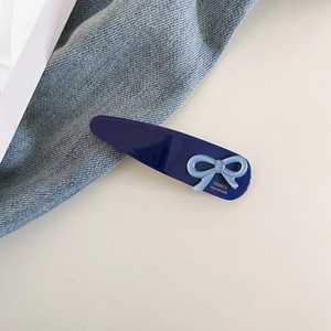 Détail d'une pince à cheveux bleue avec noeud et inscription dorée France fait à la main