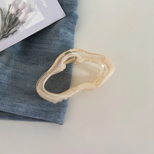 Detailed view of cream-colored jelly cloud hair claw clip on denim fabric background