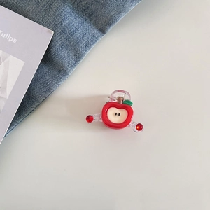 Détail d'une pince à cheveux en forme de pomme rouge avec feuille verte