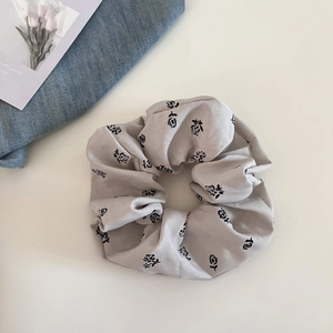 Close-up of vintage beige scrunchie with black rose floral print on woven fabric