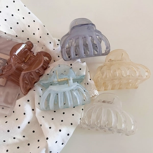 Minimalist large resin hair claws in five pastel colors on a stylish polka dot surface