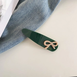 Détail de la pince à cheveux en acétate vert foncé avec nœud rose et texte fait main
