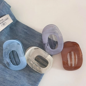 Détail de quatre pinces à cheveux colorées en acétate sur fond blanc et denim bleu