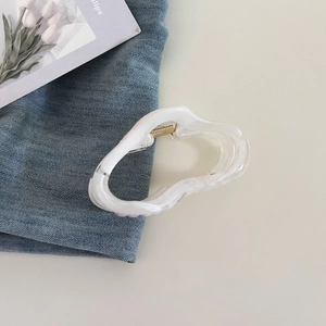 Detail of cloud shaped hair claw clip in jelly white with marble texture and gold spring