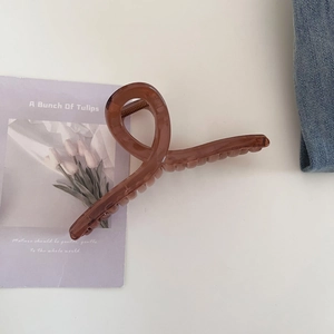 Détail d'une pince à cheveux en résine marron café sur denim avec décor de tulipes