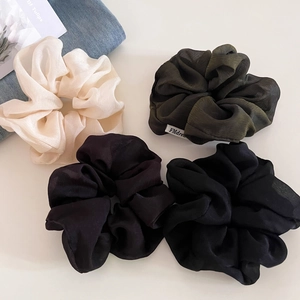 Macro shot of textured sheer tulle scrunchies in cream, green, purple and black set