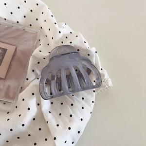 Detail view of a translucent light purple shark hair clip on a polka dot fabric background