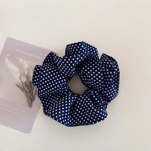 Navy blue oversized scrunchie with white polka dots on a minimalist background