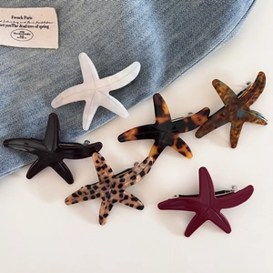 Flat lay of acetate starfish hair clips in various colors on blue denim fabric background