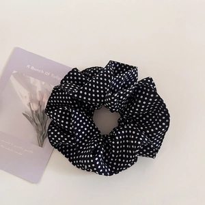 Detail view of a navy blue polka dot scrunchie with soft ruffled fabric texture