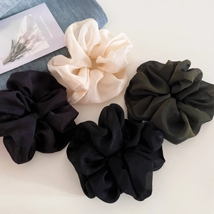 Detailed macro view of four oversized chiffon scrunchies in minimalist dark aesthetic colors