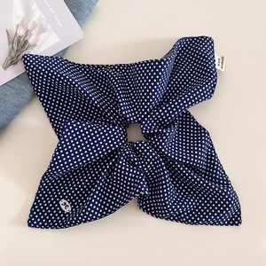 Detail of navy blue polka dot scrunchie with handmade label and bow badge on soft fabric