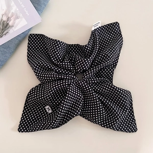 Detail of navy blue polka dot hair scrunchie with handmade label on white background