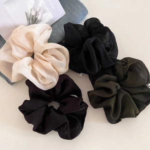 Close-up of textured organza scrunchies in champagne, black, purple and dark green colors
