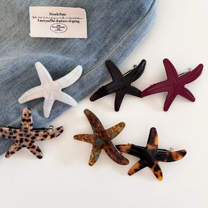 Flat lay of acetate starfish hair clips in multiple colors on blue denim fabric background