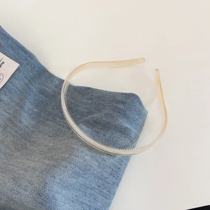 Detail view of transparent beige headband with anti-slip teeth on blue denim fabric