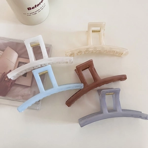 Detail showing five assorted marble resin hair claws on a minimalist white background