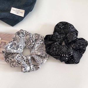 Close-up of paisley pattern scrunchies in black and white cotton fabric textures