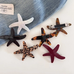 Starfish shaped acetate hair clip set in various colors on blue denim background