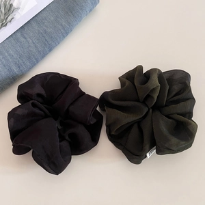 Detail of black and dark green organza scrunchies with pleated texture and brand tag