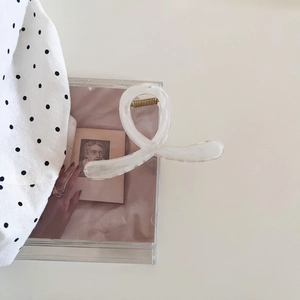 Détail d'une pince à cheveux en acrylique crème mat avec ressort doré et design torsadé