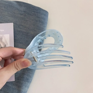 Détail d'une pince à cheveux cœur bleu clair translucide avec un ressort métallique