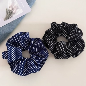 Detail of navy blue and black polka dot fabric scrunchies in a soft ruffled design