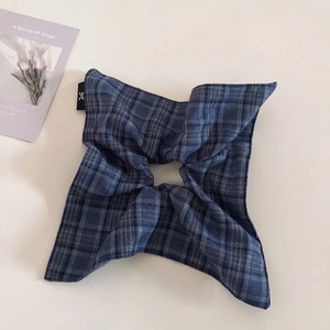 Detailed shot of navy blue plaid fabric hair accessory with a minimalist logo tag
