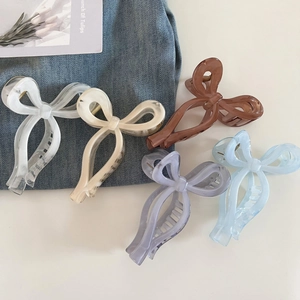Close-up of five colorful ribbon bow hair claws in marble and solid finishes