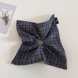 Detail of oversized navy plaid hair scrunchie with woven texture and small brand label