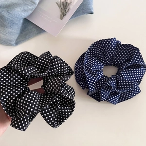 Detail of two navy and black polka dot scrunchies on a minimalist background