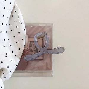 Détail d'une pince à cheveux torsadée gris-violet translucide avec ressort en métal doré
