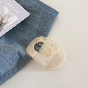 Gros plan d'une pince à cheveux en marbre crème avec texture résine sur jean