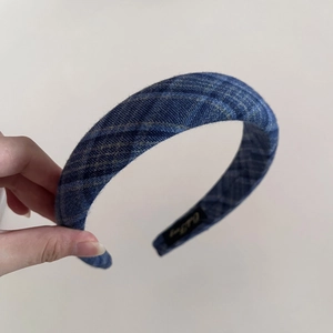 Detail view of retro navy blue checkered headband with textured fabric and inner brand label